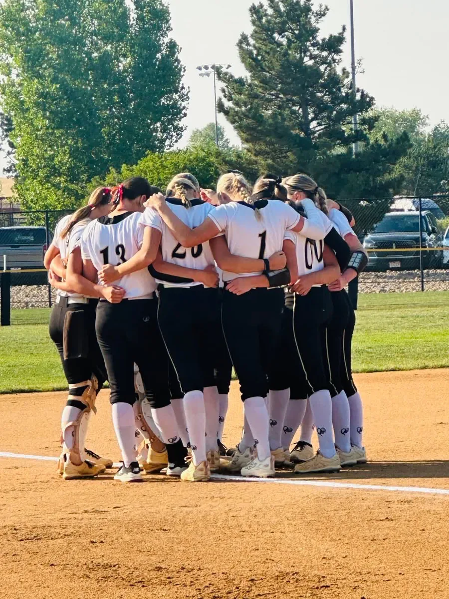 A travel softball team huddled together before taking the field